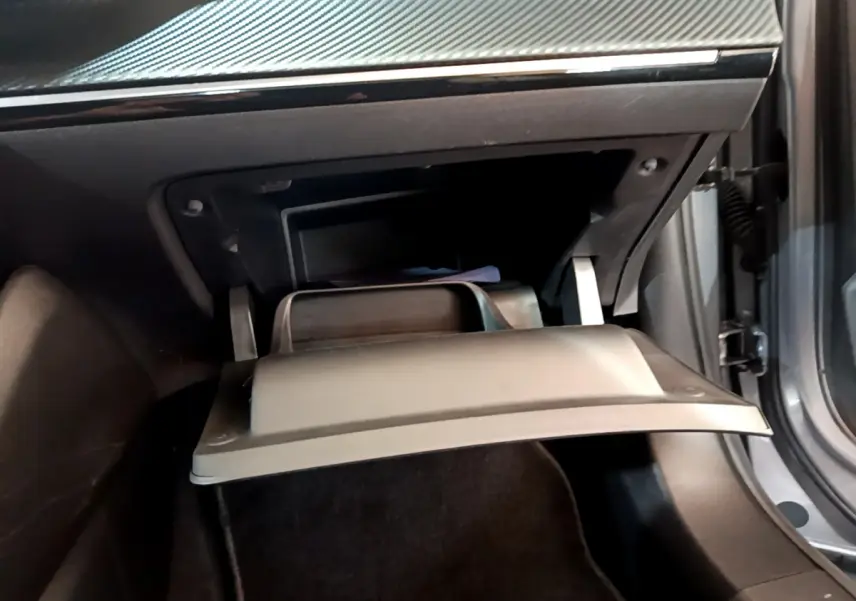 Gros plan sur la boîte à gants ouverte côté passager du Peugeot 2008 gris clair, soulignant l'intérieur noir.