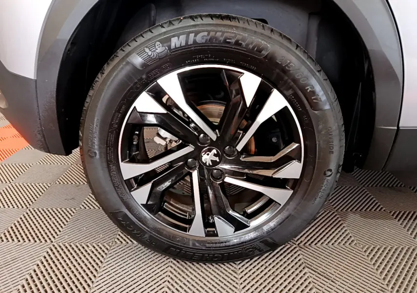 Gros plan sur la roue avant droite du Peugeot 2008 gris clair, avec jante alliage noire et argentée au design moderne.
