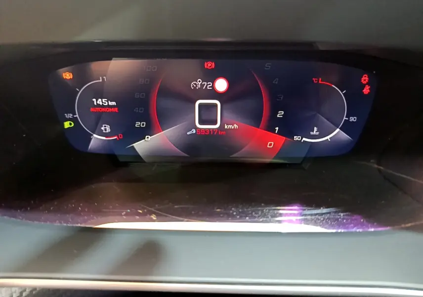 Tableau de bord numérique du Peugeot 2008 PureTech 130, affichant la vitesse et autonomie, en vue frontale rapprochée.