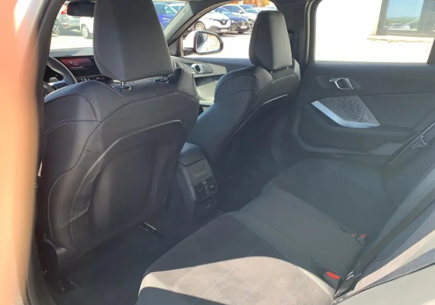 Vue intérieure arrière droite de la BMW Série 1 118D M Sport 2025 avec sellerie Alcantara noire et surpiqûres bleues.