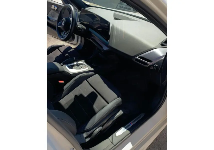 Intérieur côté conducteur de la BMW Série 1 blanche, avec sièges sport Alcantara et tableau de bord moderne M Sport.