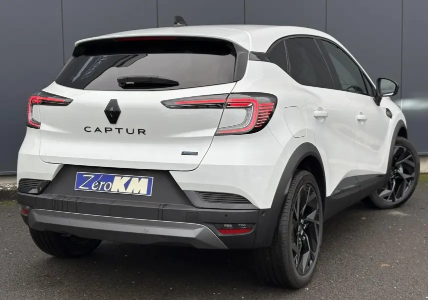 Vue 3/4 arrière droite du Renault Captur blanc nacré avec jantes noires et badge E-Tech sur la malle arrière.