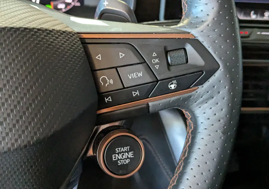 Gros plan sur le volant cuir perforé avec commandes multifonctions et bouton start/stop du CUPRA Formentor gris métallique.