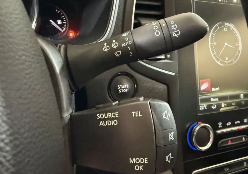 Détail intérieur du volant et commandes audio d’une Renault Mégane Intens gris foncé, avec bouton start/stop visible.