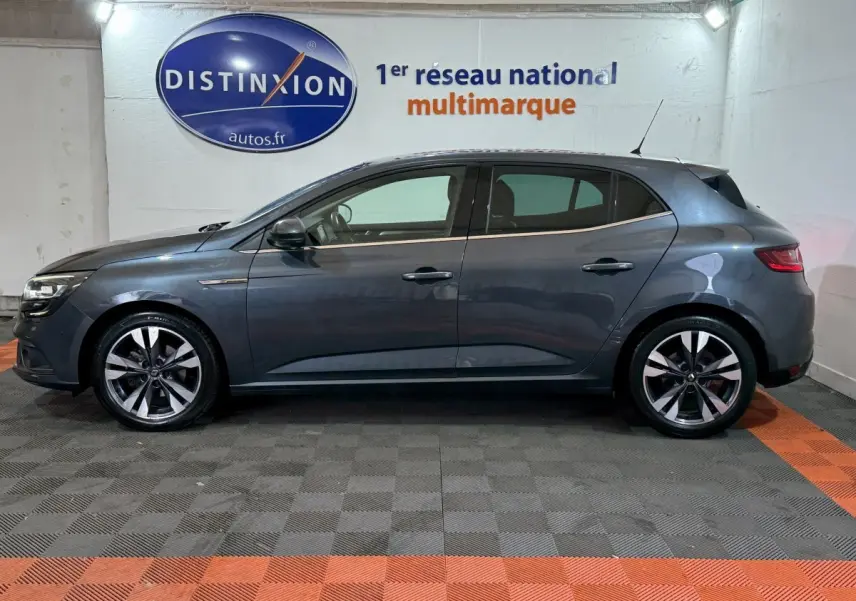 Profil côté gauche d'une Renault Mégane Intens gris foncé 2019, avec jantes alliage et vitres teintées en intérieur showroom.