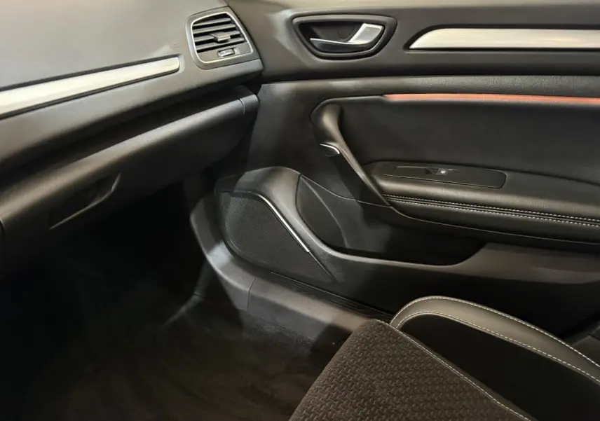 Intérieur côté passager de la Renault Mégane gris foncé, avec porte en cuir noir et détails de finition.
