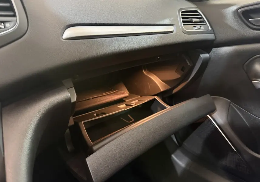 Intérieur de la Renault Mégane Intens 2019, vue côté passager sur la boîte à gants ouverte avec éclairage intérieur.