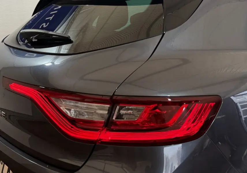 Gros plan sur le feu arrière droit rouge et blanc d’une Renault Mégane gris foncé de 2019.