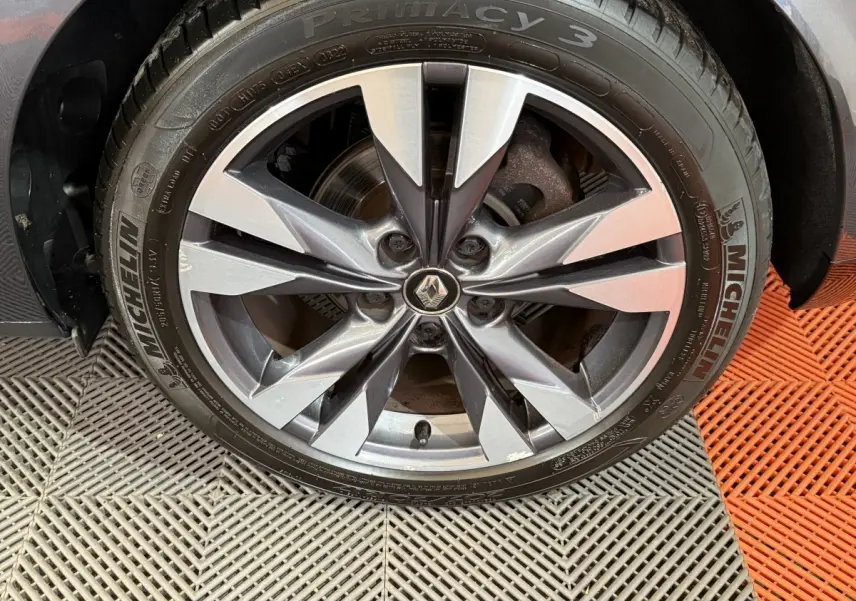 Gros plan sur la roue avant droite de la Renault Mégane gris foncé, avec jante alliage à design moderne et logo Renault central.