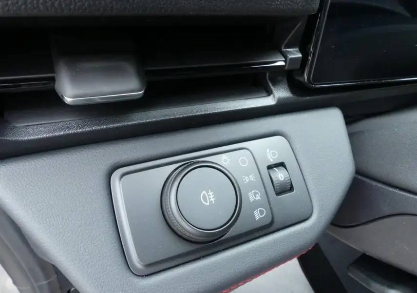 Gros plan sur le bouton de réglage des phares dans l'habitacle du Ford Puma 2025 gris métallisé.