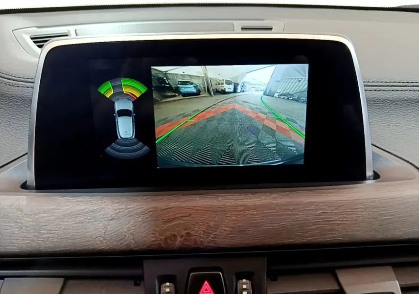 Écran tactile intérieur montrant la caméra de recul et l’aide au stationnement du BMW X2 bleu.