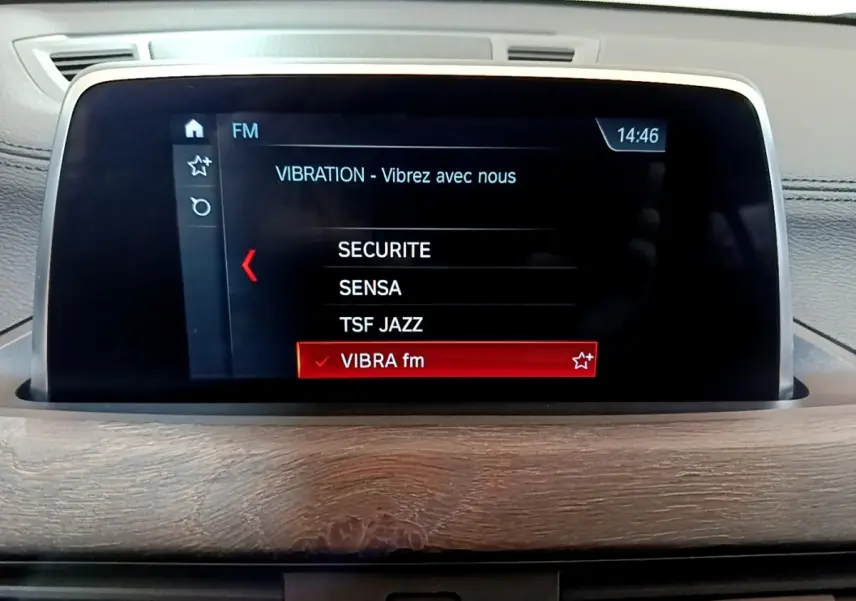 Écran tactile central du tableau de bord avec affichage radio FM dans une BMW X2 bleu 2019.