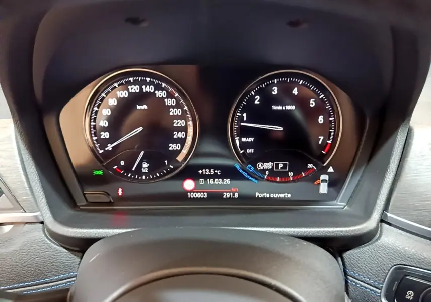 Gros plan sur le tableau de bord numérique de la BMW X2 bleu, affichant vitesse, compte-tours et informations de conduite.