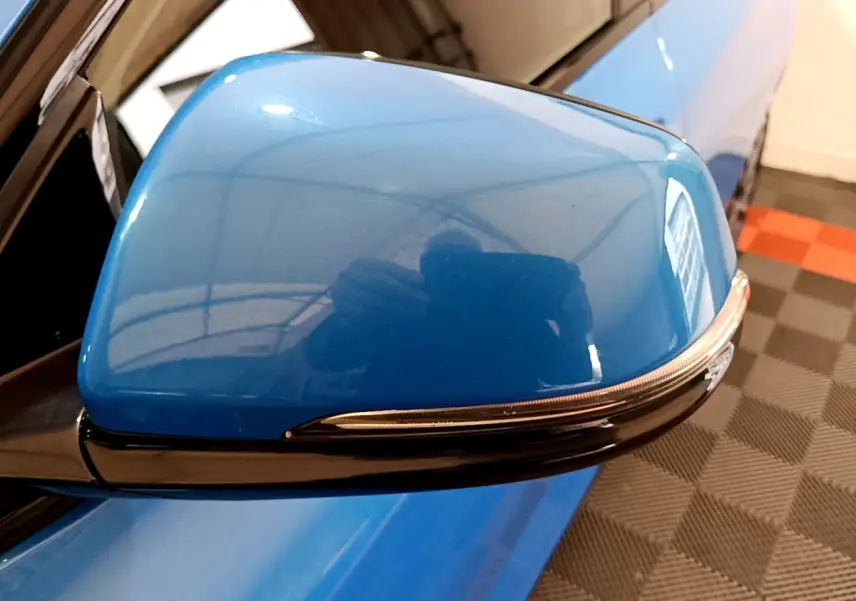 Rétroviseur côté gauche bleu brillant de la BMW X2 sDrive20i M Sport DKG7 avec clignotant intégré, vue rapprochée.