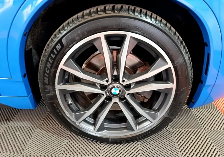 Gros plan sur la roue avant droite avec jante alliage BMW gris foncé du BMW X2 bleu sDrive20i M Sport 2019.
