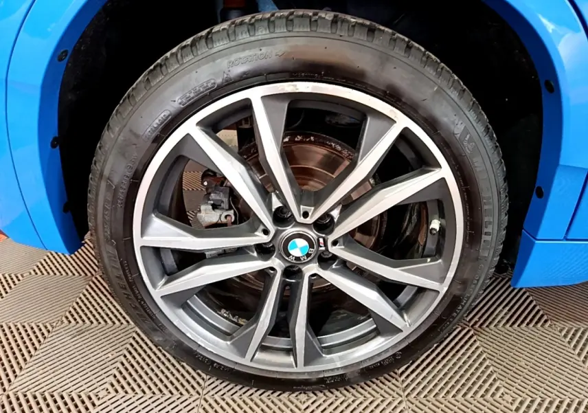 Gros plan sur la roue avant gauche d’une BMW X2 bleu 2019 avec jante alliage M Sport à dix branches.