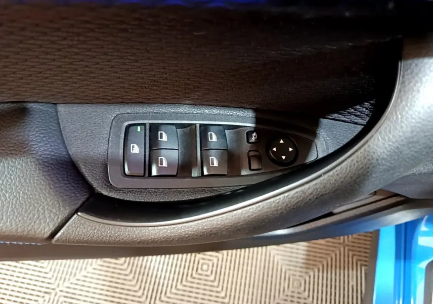 Gros plan sur les commandes des vitres et rétroviseurs côté conducteur d’une BMW X2 bleu sDrive20i M Sport 2019.