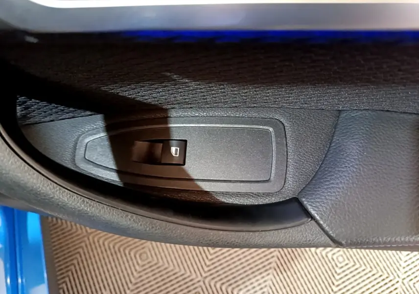 Gros plan sur la commande de lève-vitre côté conducteur d’une BMW X2 sDrive20i M Sport bleu 2019.
