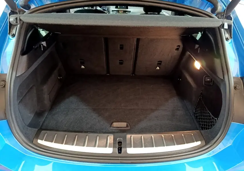 Coffre ouvert d'une BMW X2 bleu, vue arrière montrant l'espace de chargement et la banquette rabattable.