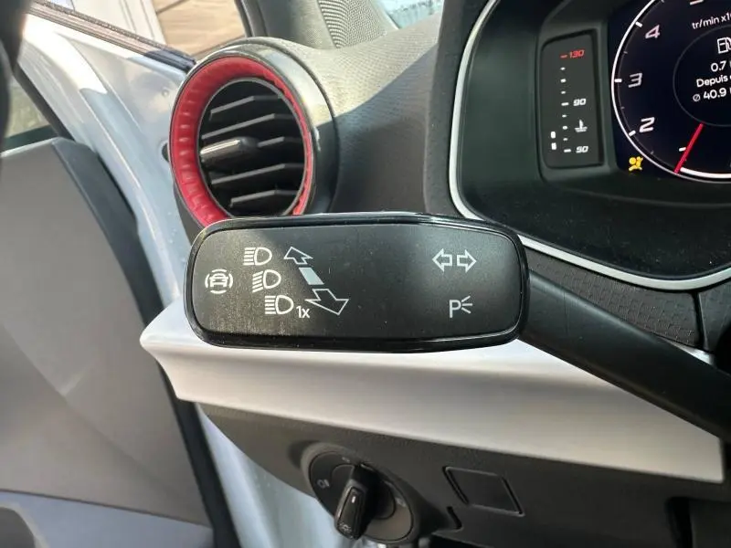 Gros plan sur la commande de clignotants à gauche dans l’habitacle du SEAT Arona blanc avec cerclage d’aération rouge.