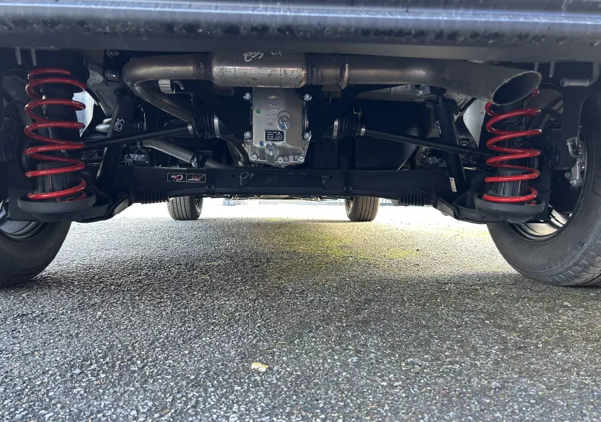 Vue en contre-plongée sous le train arrière avec ressorts rouges du DANGEL PARTNER 4x4 gris Artense.