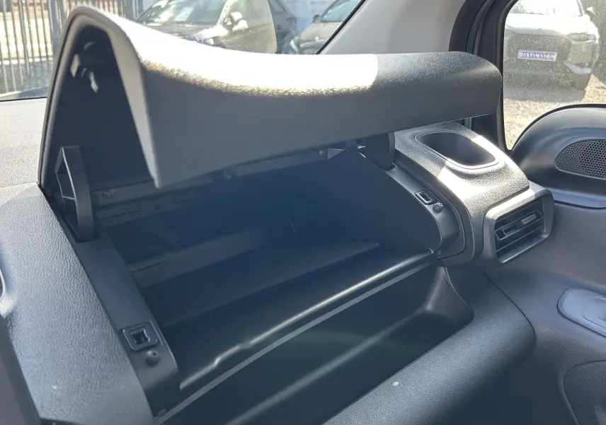 Vue intérieure sur la boîte à gants ouverte du DANGEL PARTNER 2025, soulignant les matériaux noirs texturés du tableau de bord.