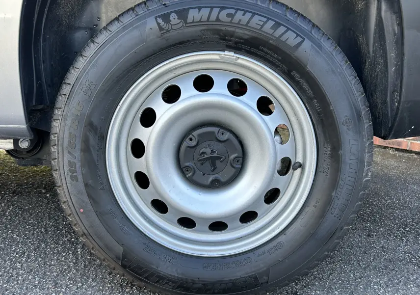 Gros plan sur la roue avant gauche du DANGEL PARTNER gris Artense avec jante acier et pneu Michelin 215/65 R16.