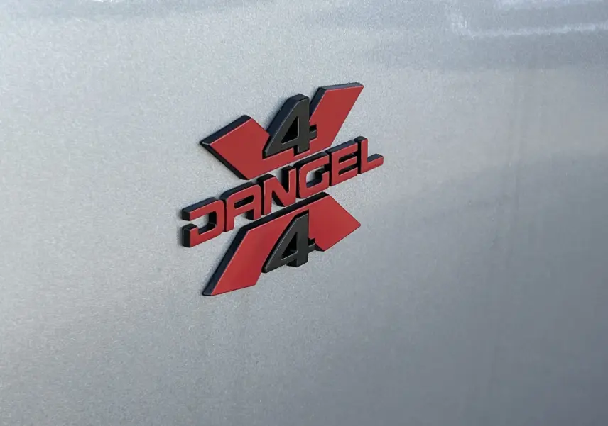 Gros plan sur l'emblème rouge et noir 4x4 DANGEL sur la carrosserie gris artense du Peugeot Partner 2025.