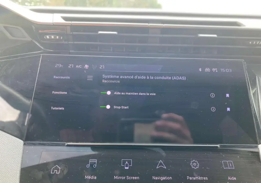 Écran tactile central de la Peugeot 308 2023 affichant les aides à la conduite dans un intérieur moderne noir.