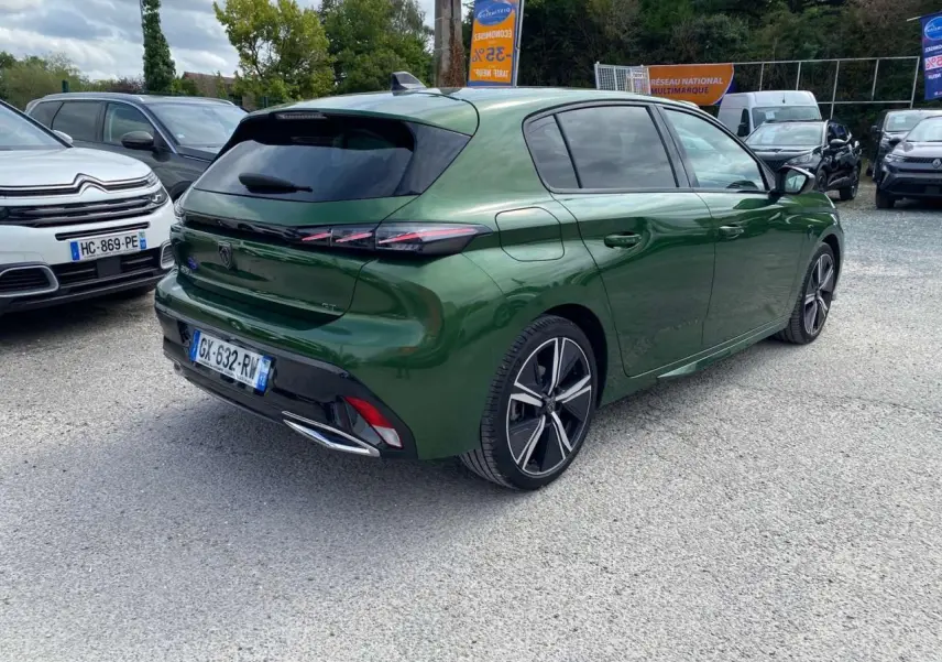 Peugeot 308 GT vert olivine vue 3/4 arrière droit sur parking avec jantes alliage et vitres teintées.