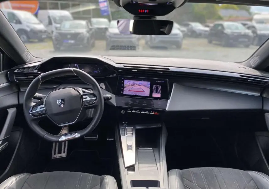 Intérieur Peugeot 308 GT 2023 vu de face, tableau de bord avec écran tactile affichant la caméra de recul.