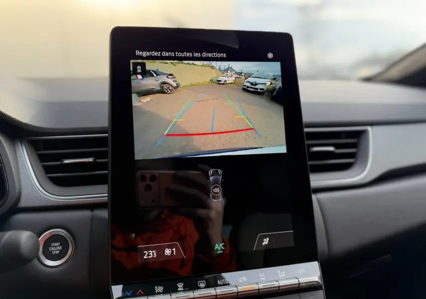 Écran tactile central montrant la caméra de recul du Renault Captur blanc nacré, intérieur avec tableau de bord noir.