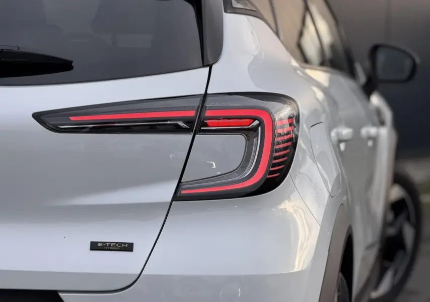 Gros plan sur l'arrière droit du Renault Captur blanc nacré, mettant en valeur le feu LED et le badge E-Tech Hybrid.