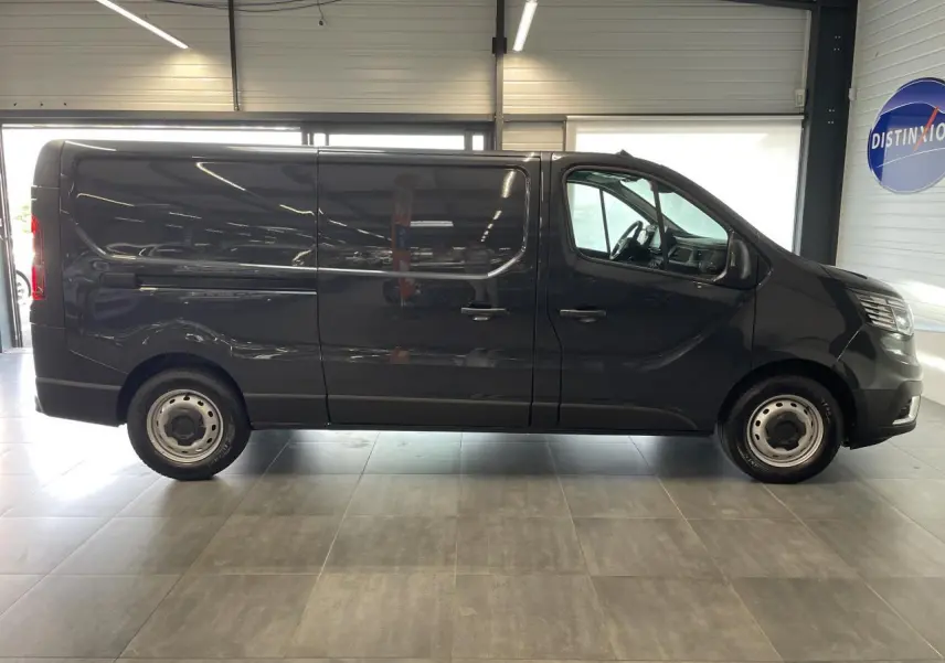 Renault Trafic Fourgon gris Comète vu de profil côté droit dans un showroom lumineux.