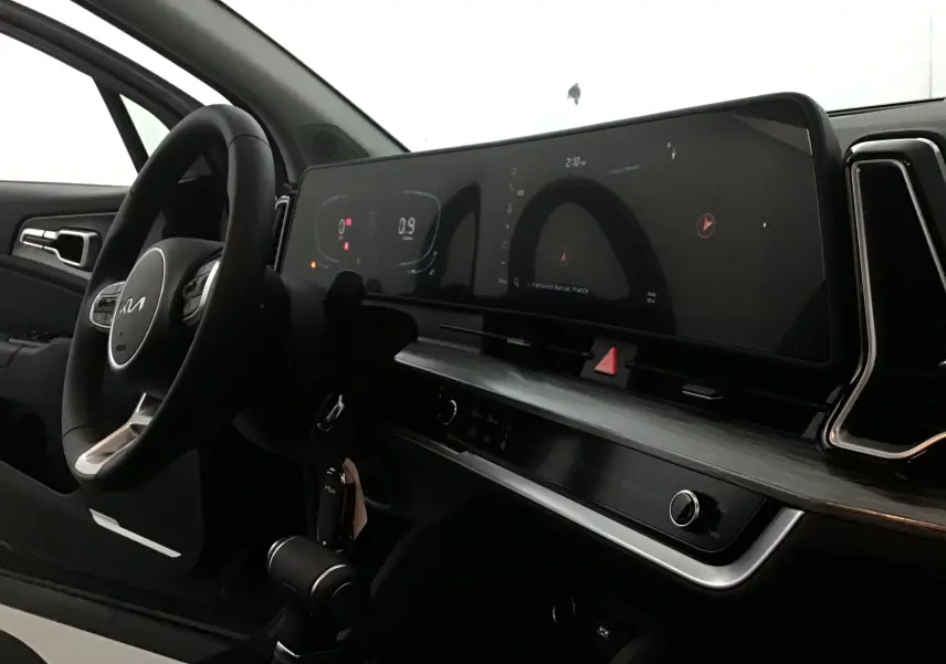 Vue intérieure côté conducteur du Kia Sportage 2025 avec tableau de bord numérique et volant cuir noir.