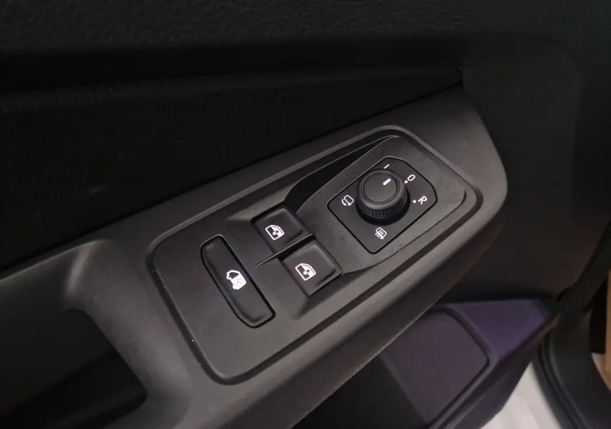 Gros plan sur les commandes des vitres et des rétroviseurs côté conducteur du Volkswagen Caddy Maxi blanc 2025.