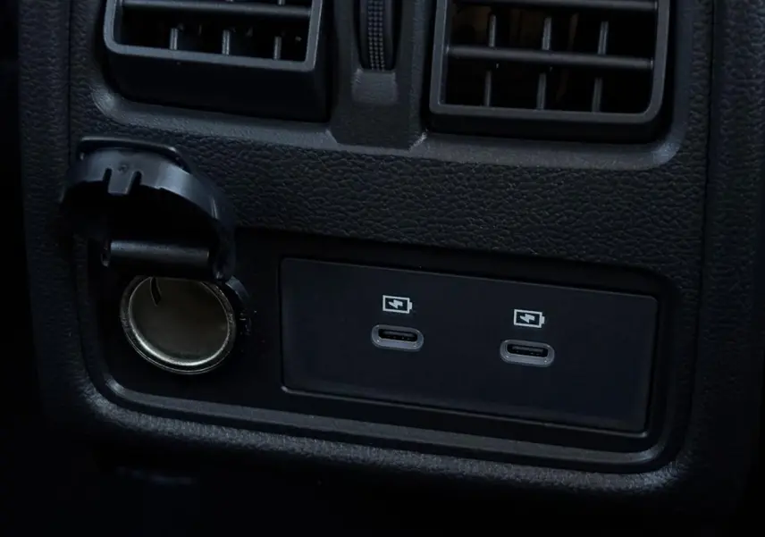 Prise USB double et allume-cigare noir en gros plan sur la console arrière du Renault Captur gris Rafale.