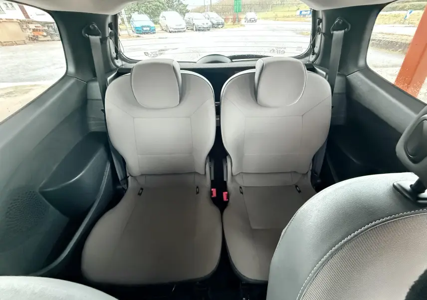 Vue arrière intérieure montrant les deux sièges arrière gris clair d’une Renault Twingo II de 2009.