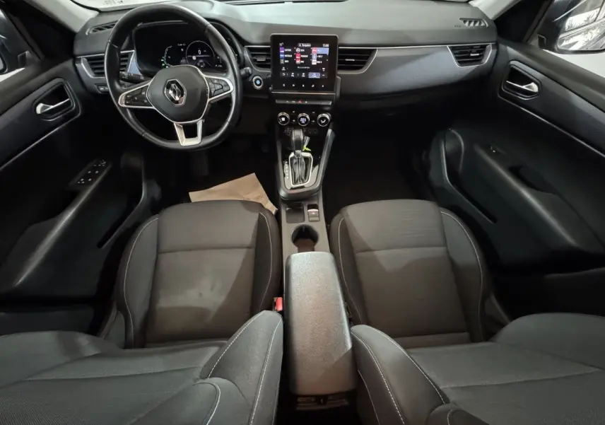 Vue intérieure avant de la Renault Arkana Business E-TECH 145, tableau de bord noir avec écran tactile central et volant multifonctions.