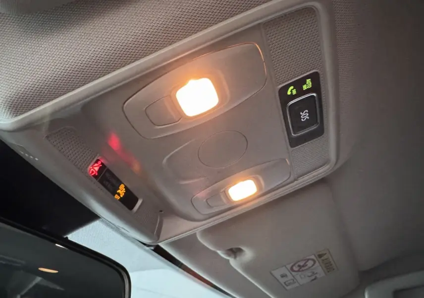 Plafonnier intérieur allumé avec boutons SOS et appels, vue en légère contre-plongée dans Renault Arkana gris foncé.