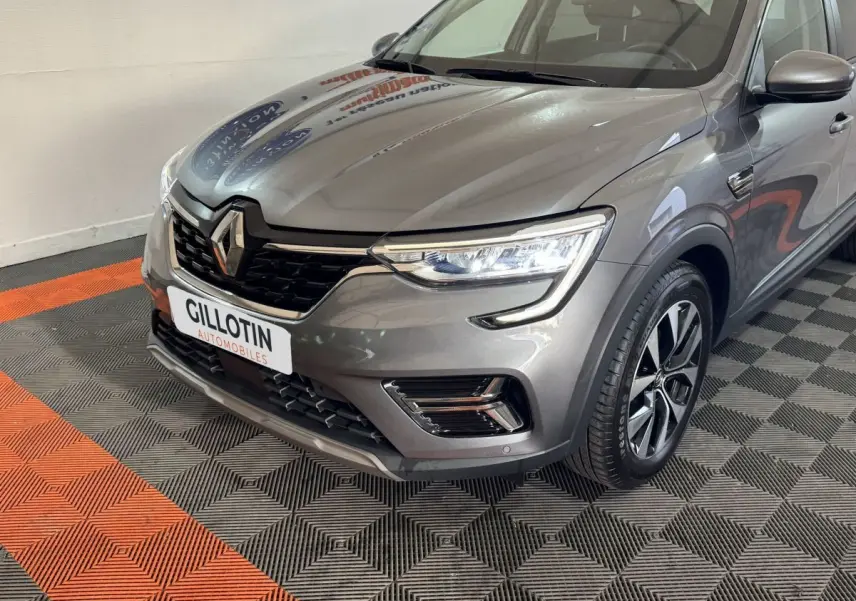 Vue 3/4 avant droit d'une Renault Arkana Business E-TECH 145 gris foncé avec phares LED et jantes alliage.