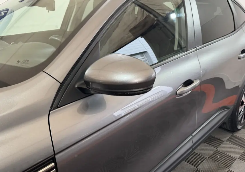 Vue rapprochée côté gauche du Renault Arkana Business E-TECH gris foncé, mettant en valeur le rétroviseur et la portière.