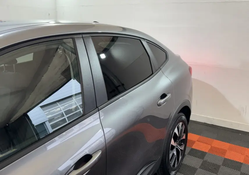 Vue côté droit arrière du Renault Arkana Business E-TECH gris foncé, mettant en valeur la porte et la roue arrière.