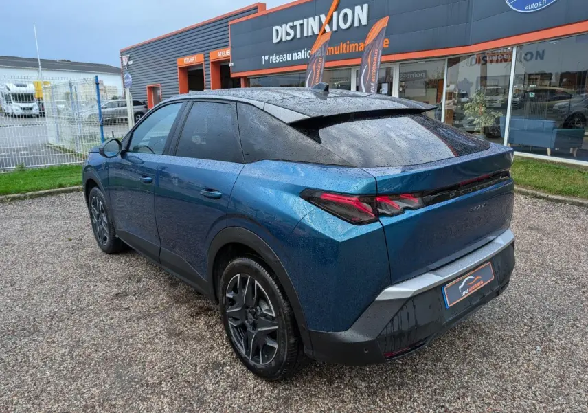 Vue 3/4 arrière droite du Peugeot 3008 GT hybride bleu métallisé avec toit noir et feux arrière à griffes LED.
