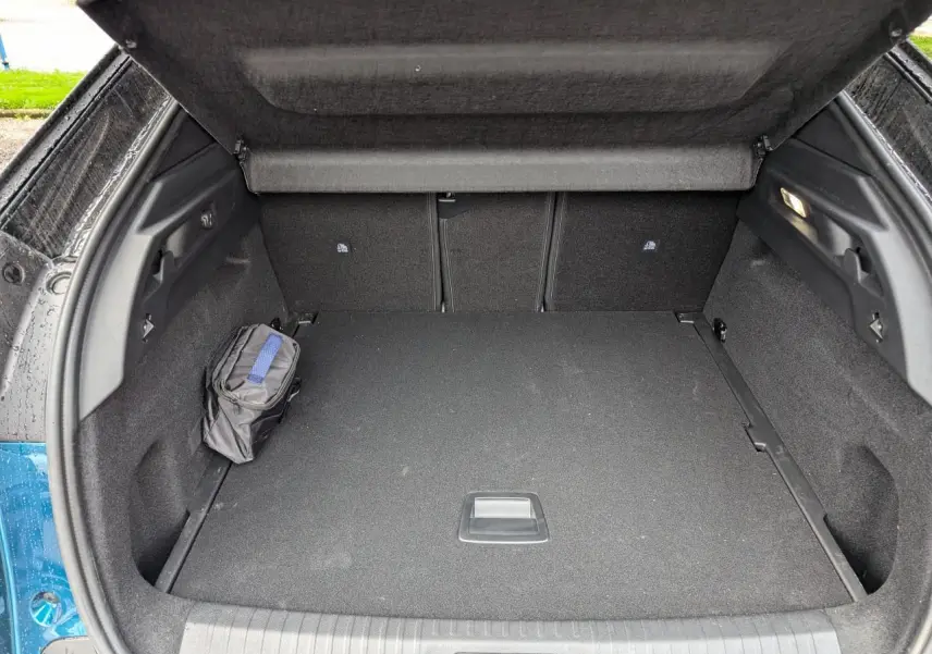 Coffre ouvert d’un Peugeot 3008 bleu métallisé, montrant un espace de chargement propre avec trousse noire sur le côté.