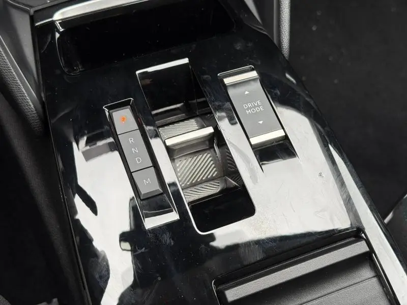 Gros plan sur la console centrale noire brillante du Citroën C4 X 2024 avec commandes de boîte automatique et mode de conduite.