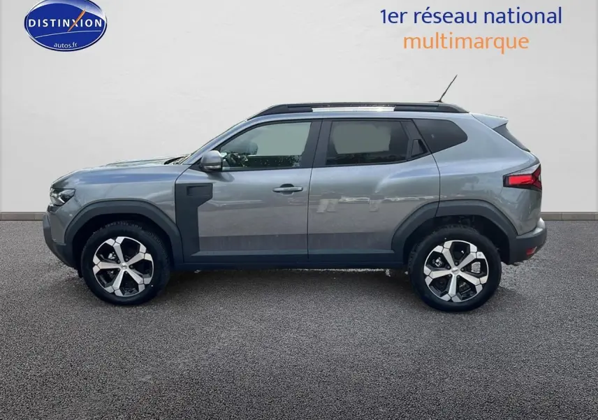 Profil droit du Dacia Duster 2025 gris schiste avec jantes alliage et barres de toit noires visibles.