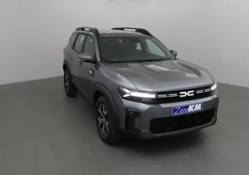 SUV Dacia Bigster gris schiste vu en 3/4 avant droit avec calandre moderne et feux LED allumés.