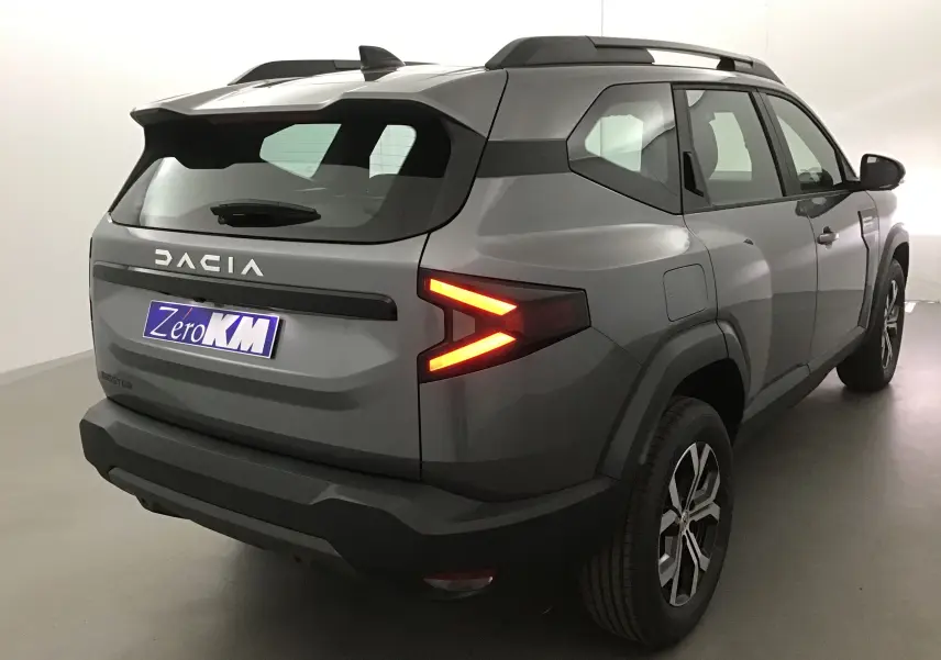 Vue 3/4 arrière droite du Dacia Bigster gris schiste avec feux arrière allumés et jantes alliage 17 pouces.