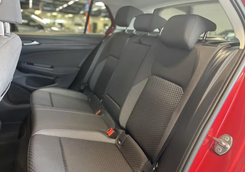 Vue intérieure côté droit sur la banquette arrière noire de la Volkswagen Golf rouge métallisée, avec ceintures visibles.